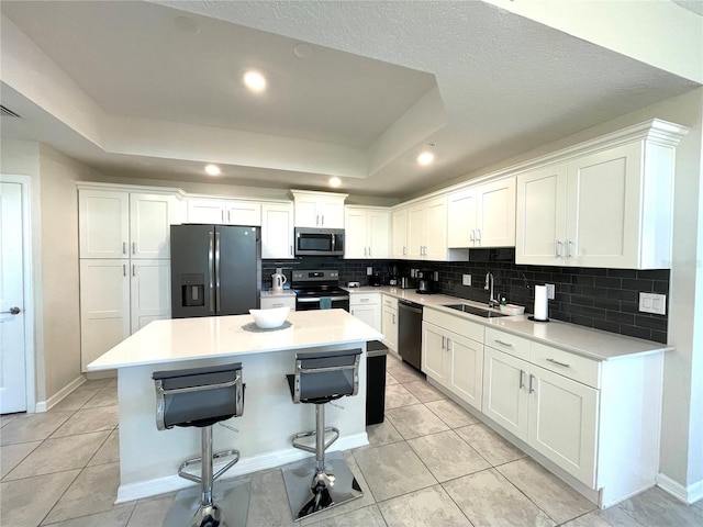 kitchen featuring a kitchen island, decorative backsplash, sink, white cabinets, and appliances with stainless steel finishes