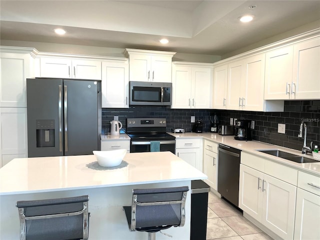 kitchen with sink, white cabinets, light tile patterned flooring, appliances with stainless steel finishes, and tasteful backsplash