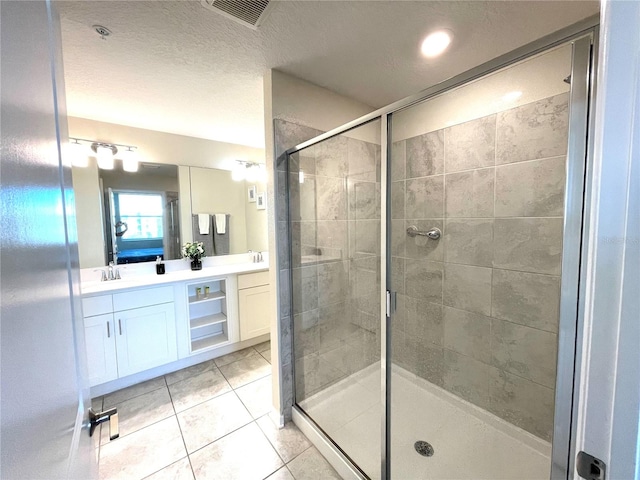 bathroom with vanity, a textured ceiling, tile patterned flooring, and a shower with door