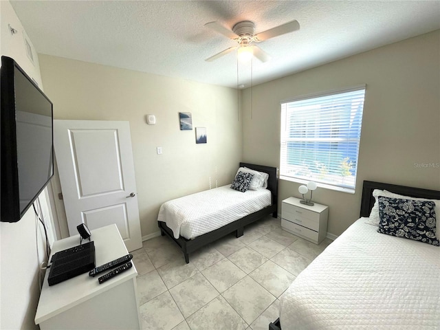 bedroom featuring ceiling fan, a textured ceiling, and light tile patterned floors