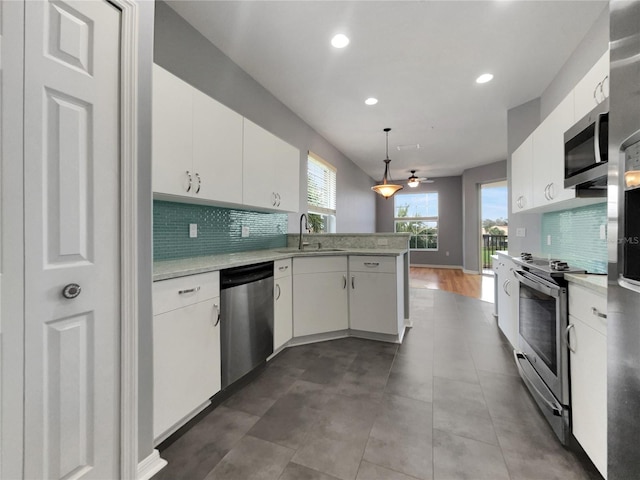 kitchen featuring sink, kitchen peninsula, white cabinetry, stainless steel appliances, and pendant lighting