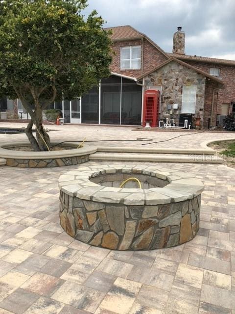 rear view of house with a patio, an outdoor fire pit, and a sunroom