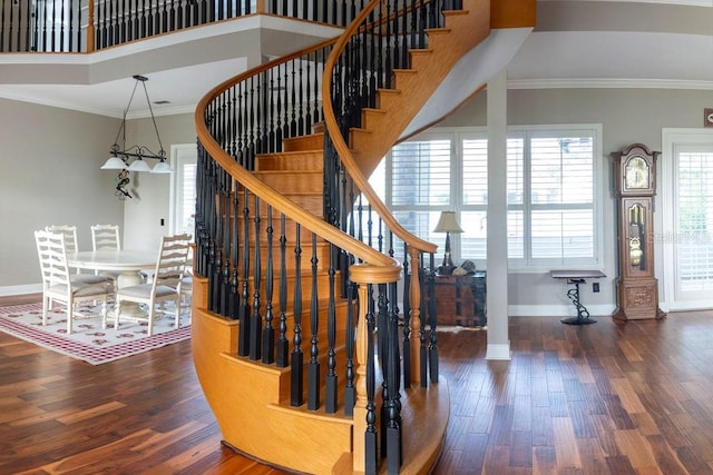 stairway featuring crown molding, wood-type flooring, and a high ceiling