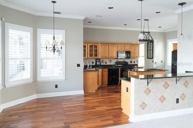 kitchen featuring sink, a kitchen breakfast bar, dark hardwood / wood-style floors, decorative light fixtures, and black appliances