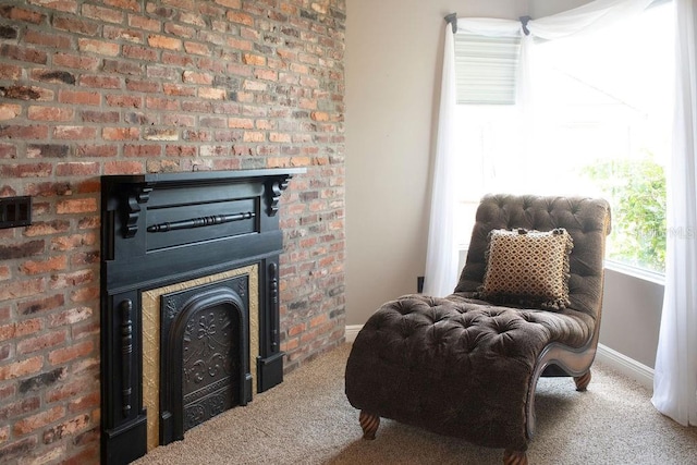 living area featuring carpet flooring and brick wall