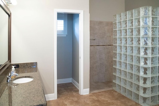 bathroom with tile patterned flooring, vanity, and a tile shower