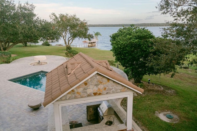 view of pool with a water view, a patio area, and a lawn