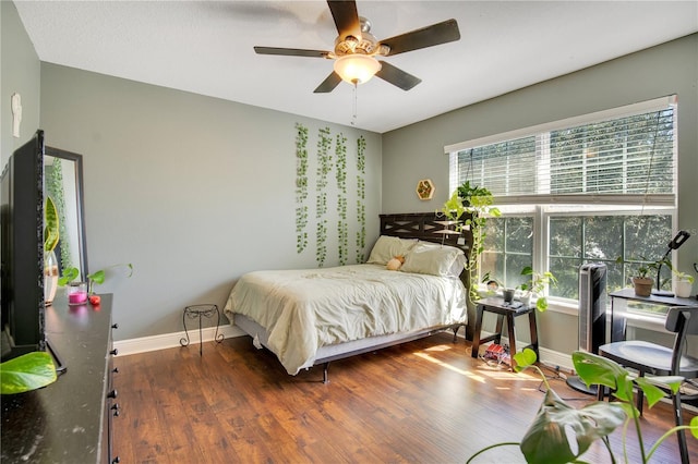 bedroom with dark hardwood / wood-style flooring and ceiling fan