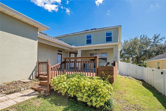 back of house with a wooden deck and a yard