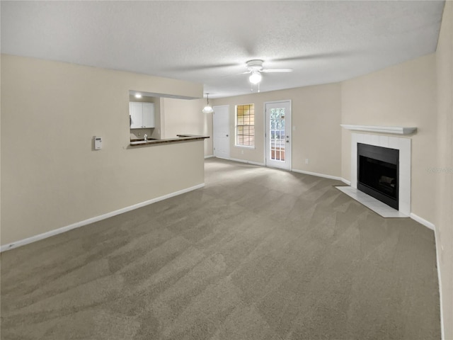 unfurnished living room featuring ceiling fan, a textured ceiling, and carpet floors