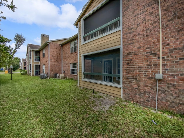 rear view of house with central AC and a yard