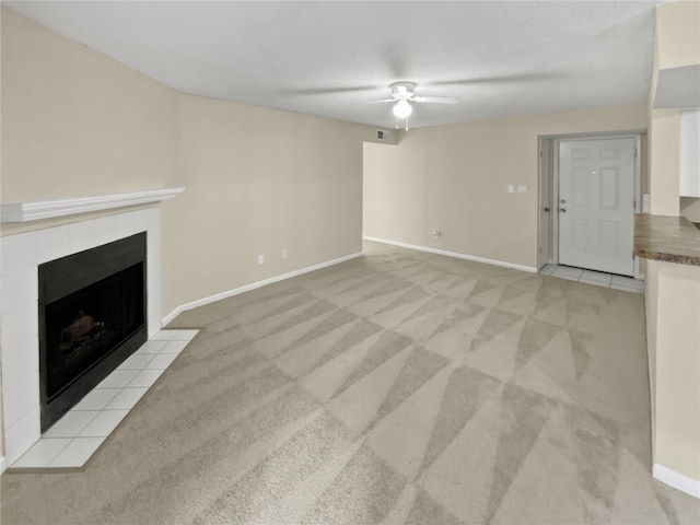 unfurnished living room with light colored carpet, a tile fireplace, and ceiling fan