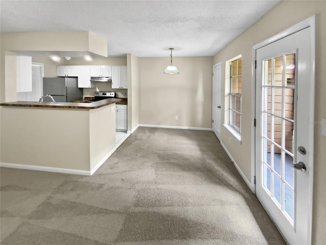 kitchen featuring kitchen peninsula, light carpet, pendant lighting, white cabinets, and stainless steel refrigerator