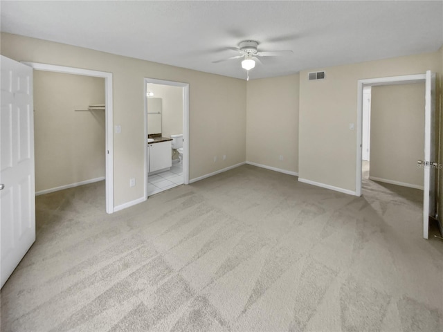 unfurnished bedroom featuring a spacious closet, ceiling fan, a closet, and light colored carpet