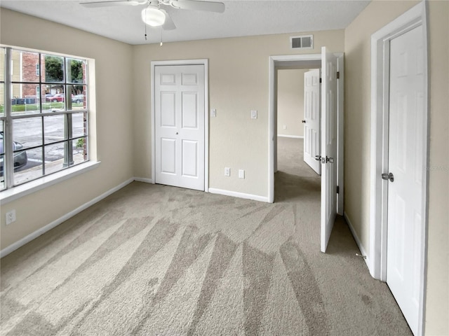 unfurnished bedroom featuring light carpet, a closet, and ceiling fan