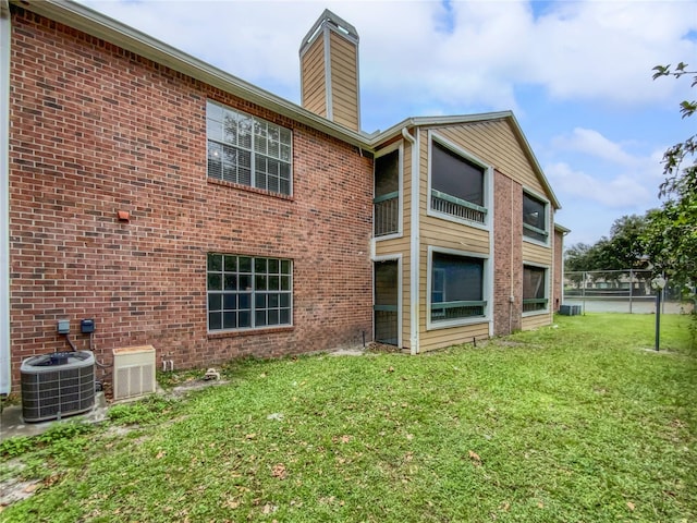 back of property with cooling unit, a yard, and a balcony