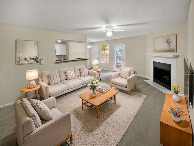 living room featuring carpet flooring, a textured ceiling, a fireplace, and ceiling fan