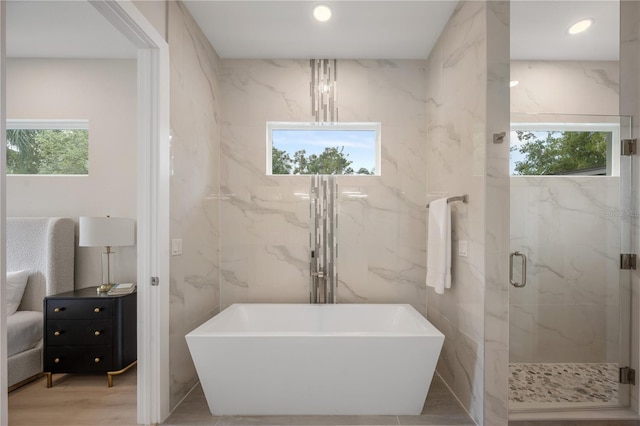 full bath with a marble finish shower, recessed lighting, wood finished floors, a soaking tub, and tile walls