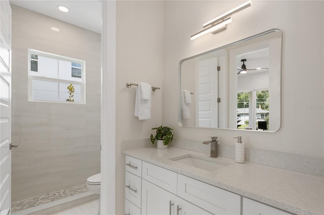 bathroom with recessed lighting, tiled shower, toilet, and vanity