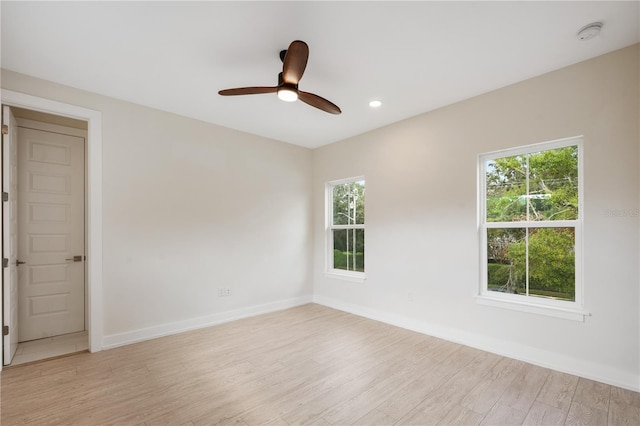 unfurnished room with plenty of natural light, baseboards, light wood finished floors, and ceiling fan