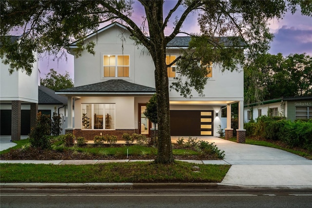 view of front facade featuring brick siding, stucco siding, driveway, and a garage