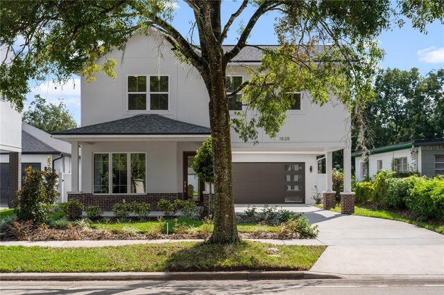 view of front facade featuring concrete driveway, a garage, brick siding, and stucco siding