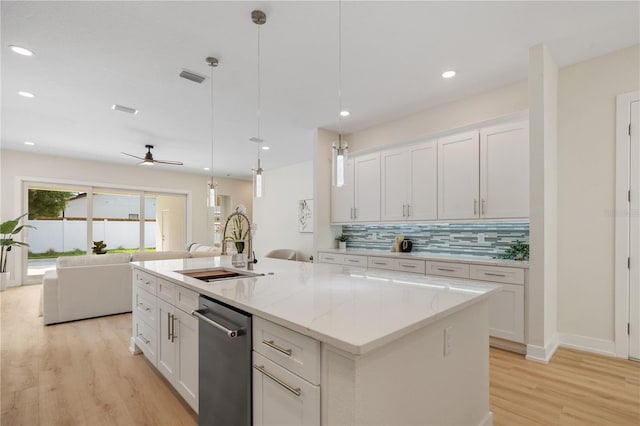 kitchen featuring tasteful backsplash, dishwasher, white cabinetry, and a sink