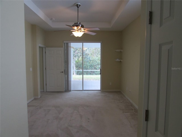 carpeted spare room featuring ceiling fan and a raised ceiling