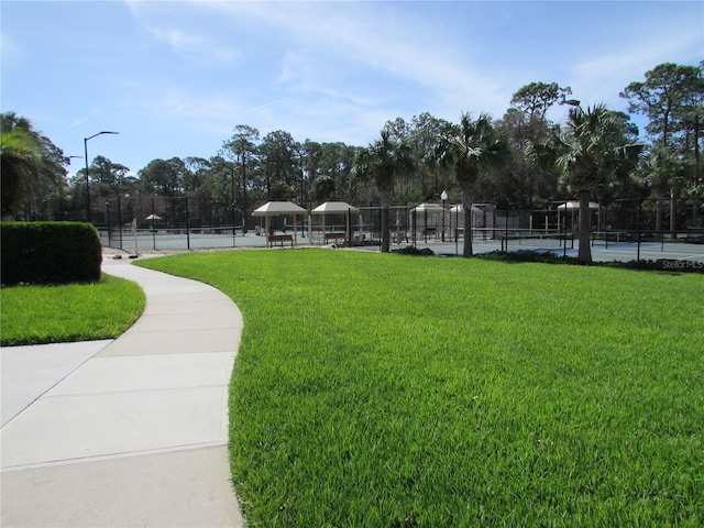 view of community featuring a lawn and tennis court