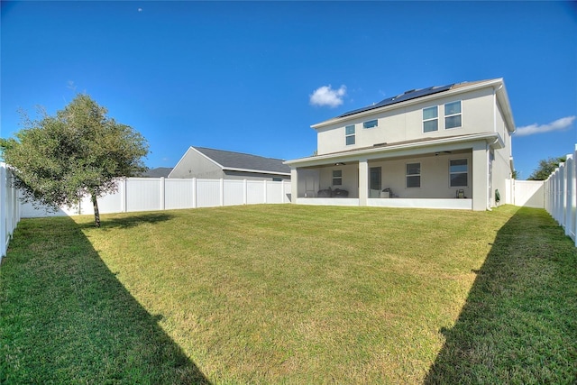 rear view of property with ceiling fan and a lawn