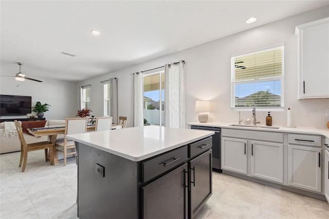 kitchen featuring sink, dishwasher, a center island, ceiling fan, and white cabinets