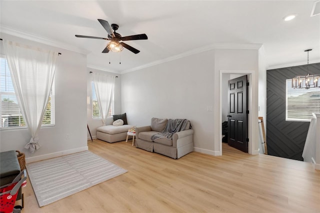 living room with light hardwood / wood-style flooring, ornamental molding, and ceiling fan with notable chandelier