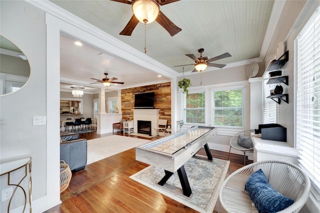 living room with crown molding, hardwood / wood-style flooring, a large fireplace, and ceiling fan