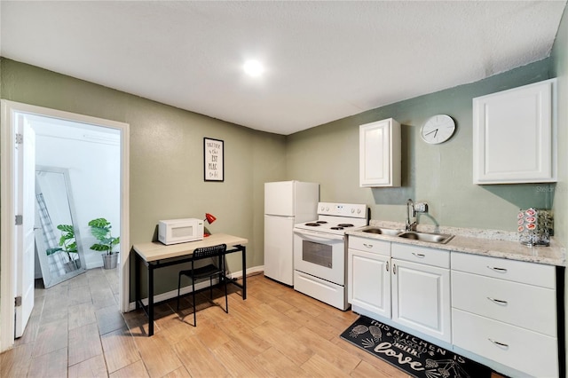 kitchen featuring white appliances, light stone countertops, sink, white cabinets, and light hardwood / wood-style flooring