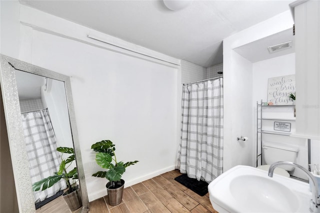 bathroom featuring toilet, sink, a shower with shower curtain, and hardwood / wood-style floors