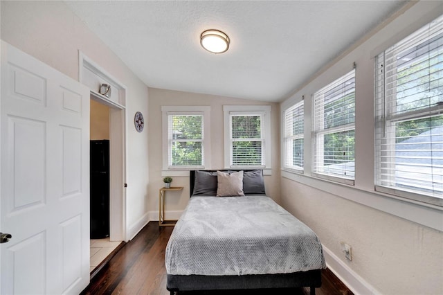 bedroom featuring a textured ceiling, lofted ceiling, multiple windows, and dark hardwood / wood-style floors