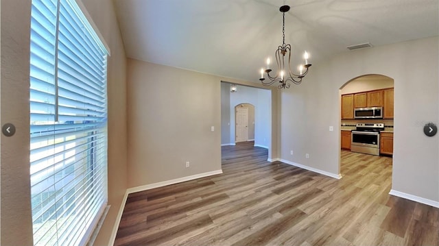 interior space with a notable chandelier, vaulted ceiling, and light wood-type flooring