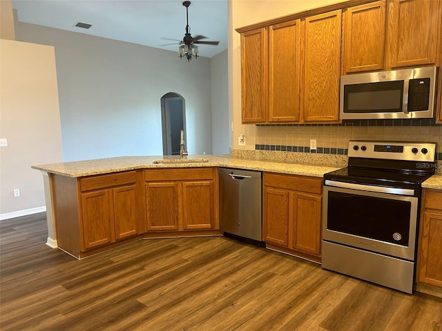 kitchen with tasteful backsplash, appliances with stainless steel finishes, sink, kitchen peninsula, and dark wood-type flooring