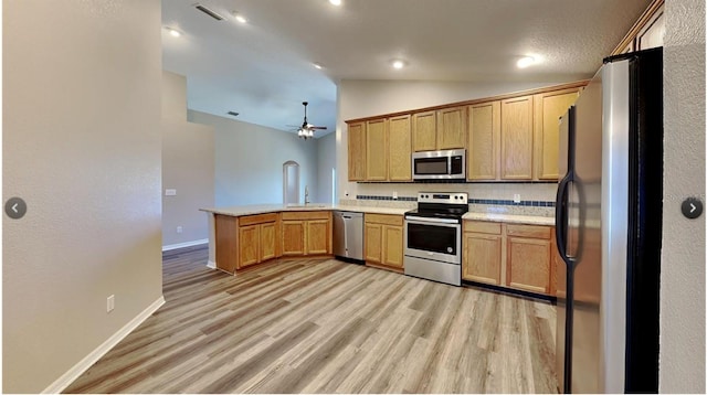 kitchen featuring appliances with stainless steel finishes, lofted ceiling, light hardwood / wood-style floors, and kitchen peninsula