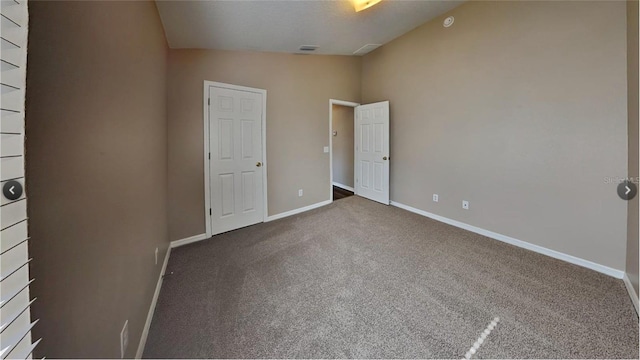 unfurnished bedroom featuring lofted ceiling and dark carpet