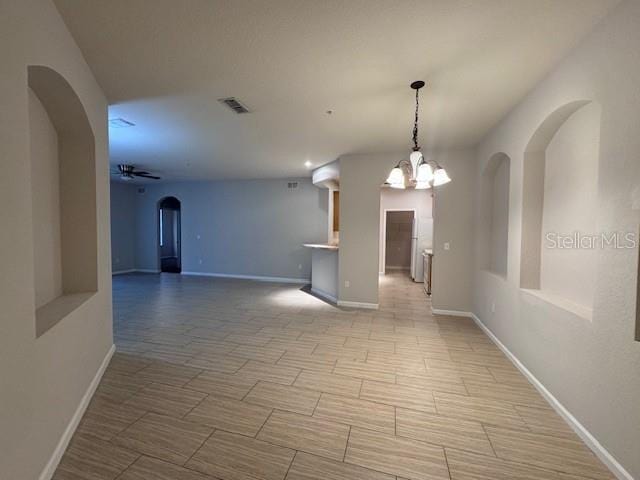 spare room with ceiling fan with notable chandelier