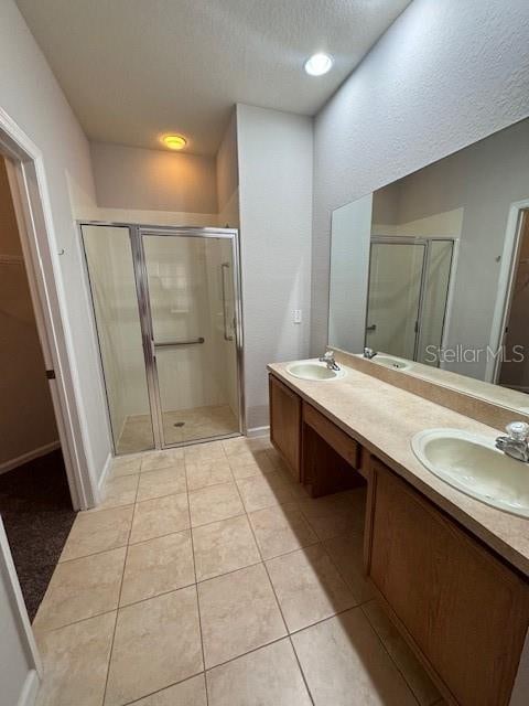 bathroom featuring a shower with door, vanity, a textured ceiling, and tile patterned flooring