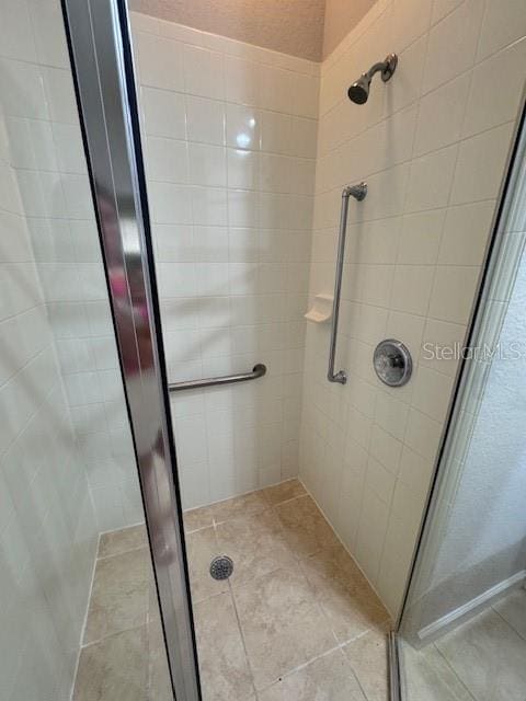 bathroom with a shower with shower door and tile patterned floors