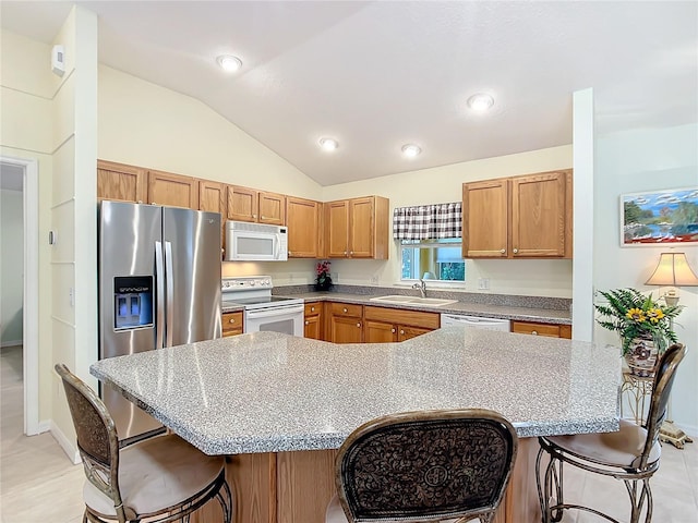 kitchen featuring lofted ceiling, sink, white appliances, and a breakfast bar