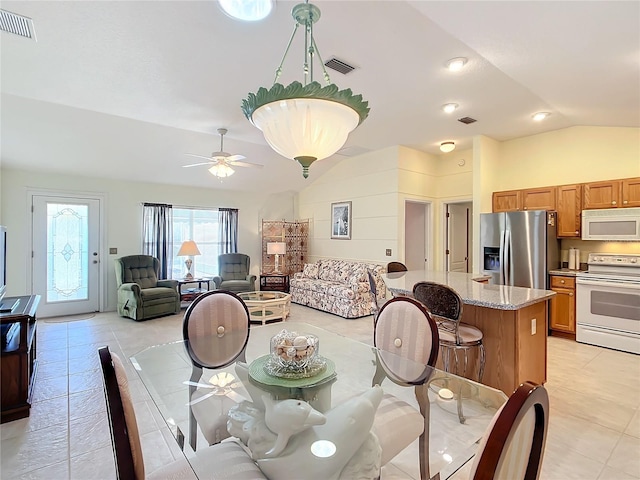 dining space with ceiling fan, vaulted ceiling, and light tile patterned floors