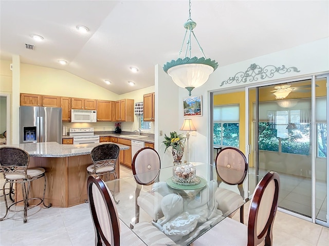 dining area with sink, light tile patterned floors, and vaulted ceiling