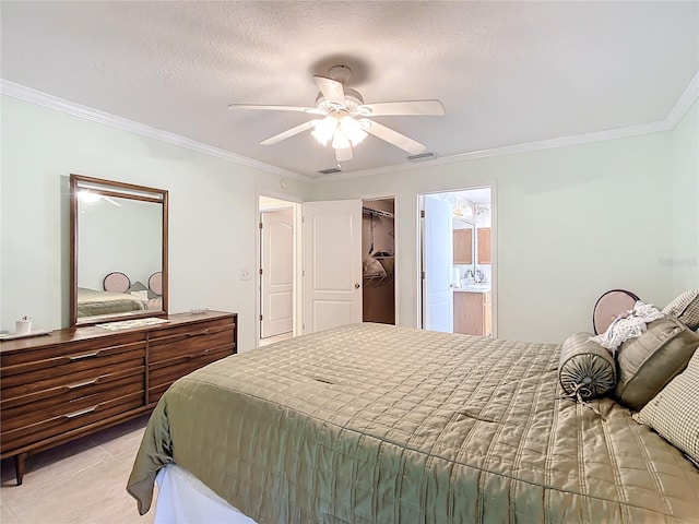 tiled bedroom featuring a walk in closet, a closet, ceiling fan, connected bathroom, and ornamental molding