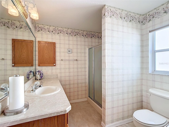 bathroom with a shower with door, vanity, toilet, and tile patterned floors