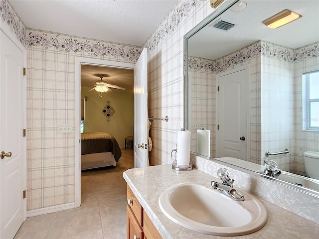 bathroom with tile patterned floors, toilet, vanity, a textured ceiling, and ceiling fan