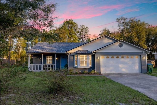 ranch-style home with a porch, a yard, and a garage